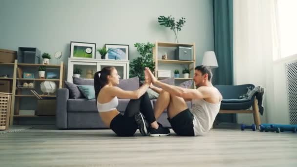 Joven mujer y hombre haciendo abdominales juntos y aplaudiendo las manos practicando en plano — Vídeos de Stock