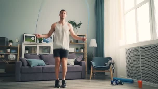 スポーツウェアやスニーカーを着て自宅で一人でスポーツマンジャンプロープトレーニング — ストック動画
