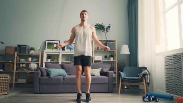 Fiatalember jumping kötél zárt otthon visel sportruházat és sportcipők — Stock videók