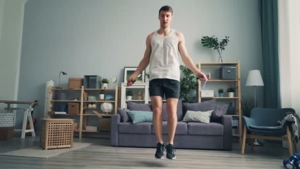 Esportivo cara estudante pulando corda no apartamento exercitando sozinho curtindo esportes — Vídeo de Stock