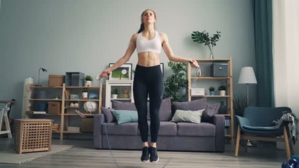 Slim jeune sportive saut à la corde dans l'appartement axé sur l'exercice cardio — Video