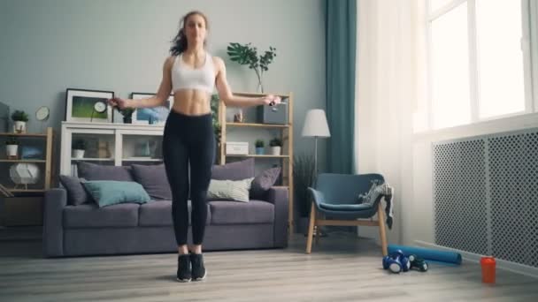 Smal flicka i leggings och topp hopprep hemma koncentrerat på aktivitet — Stockvideo