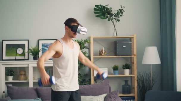 Modern kille idrotts utövare utbildning med hantlar hemma ensam klädd i ar glasögon — Stockvideo