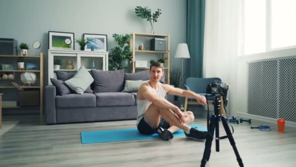 Young man vlogger recording video talking and exercising abdominal muscles — Stock Video