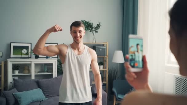Neşeli adam sporcu kas vücut gösterilen smartphone kamera için poz — Stok video