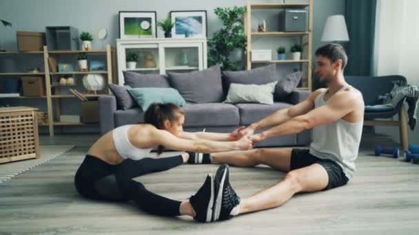 Chica y chico estirando el cuerpo en pareja en casa tomados de la mano a continuación, haciendo high-five — Vídeo de stock