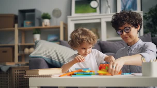 Ευτυχισμένο παιδί παίζει με ξύλινα μπλοκ κτιρίων με τη μαμά στο σπίτι επικεντρώθηκε σε παιχνίδι — Αρχείο Βίντεο