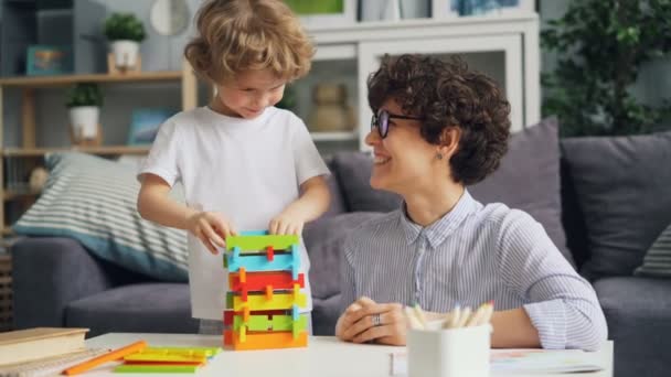 Allegro ragazza mamma giocare con il suo piccolo figlio con blocchi di legno e ridere — Video Stock