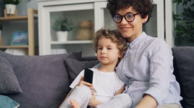 Çok güzel Tv izlerken, evde kanepenin üzerinde konuşurken çocuk ve annesi genç kadın