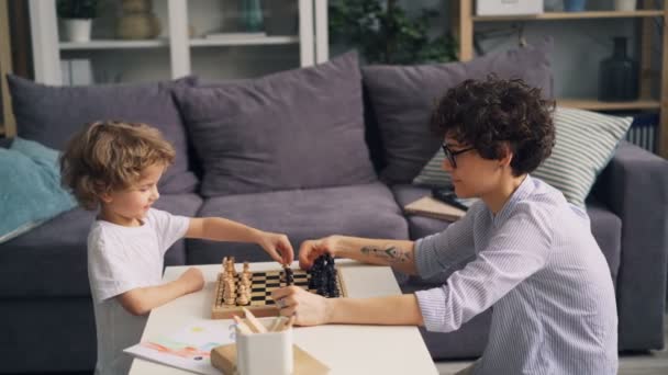 Lyckliga familjen mor och son spelar schack hemma flytta bitar ombord — Stockvideo