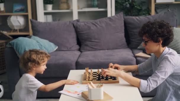 Pequeño niño es feliz después del juego de ajedrez celebrando y haciendo chocar los cinco con la madre — Vídeo de stock