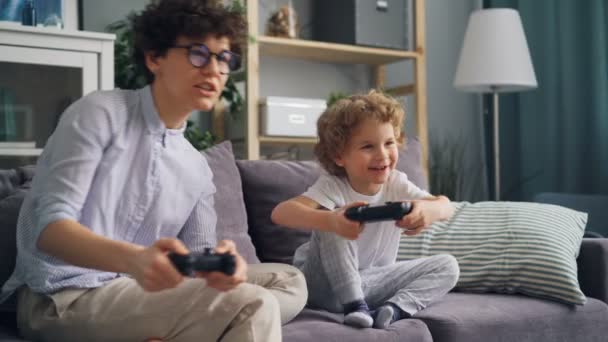 Família feliz mãe e filho jogando videogames no apartamento se divertindo juntos — Vídeo de Stock