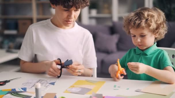 Kisfiú segít ő anya tervező otthon színes papír kollázs létrehozása — Stock videók