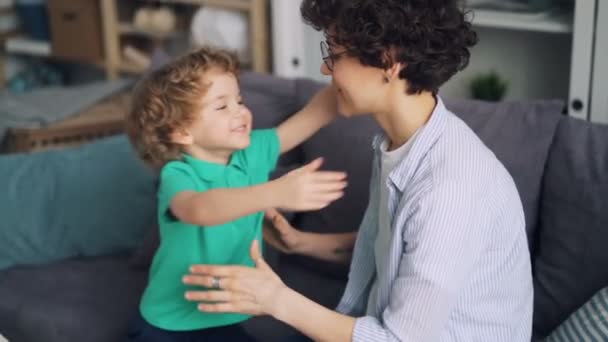 Movimento lento de uma criança amorosa abraçando sua mãe expressando amor em casa — Vídeo de Stock