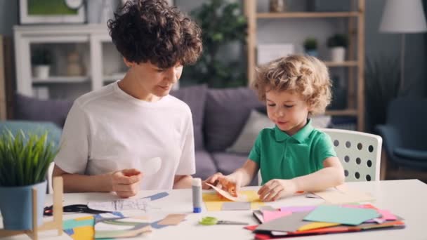 Familia creativa mamá y niño pequeño haciendo collages con papel, tijeras y pegamento — Vídeo de stock