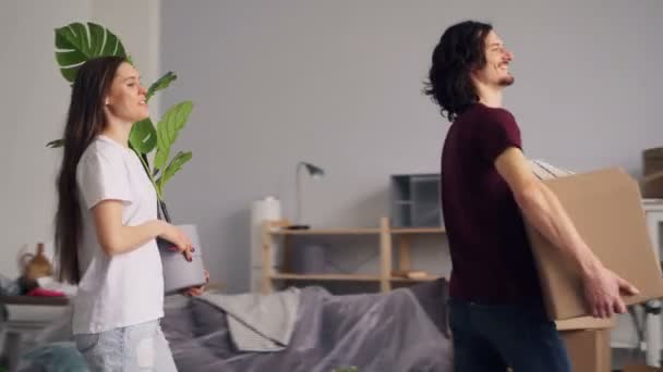 Young man and woman bringing things in boxes to new apartment and kissing — Stock Video