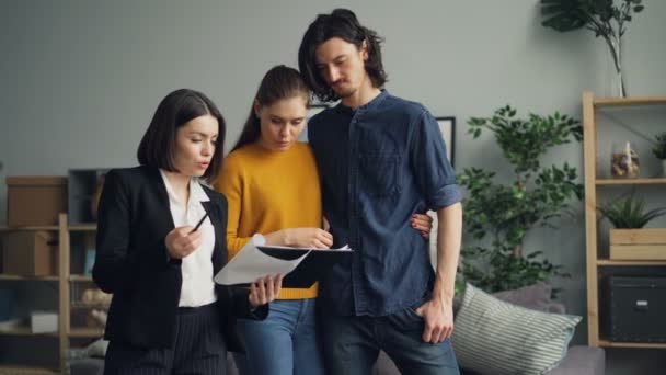 Agent immobilier montrant des documents à l'homme et à la femme, les gens parlent lecture — Video