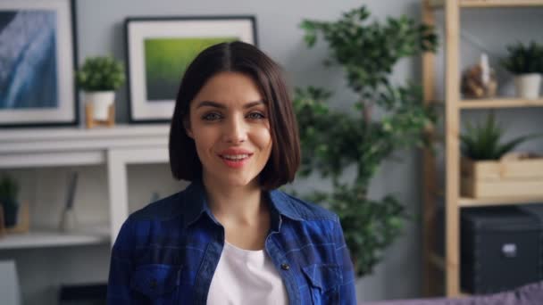 Медленный портрет красивой женщины в квартире, улыбающейся в камеру — стоковое видео