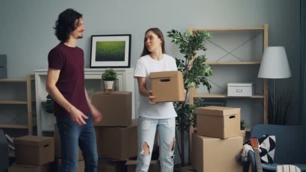 Menina e cara carregando coisas em caixas durante a mudança no novo apartamento — Vídeo de Stock