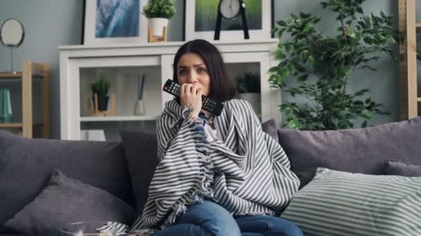 Zoom de chica emocional viendo la película en la televisión sosteniendo el control remoto en casa — Vídeos de Stock