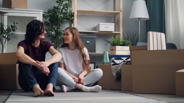 Flicka som ger unga mannen nycklar sedan kysser sitter på golvet i nytt hus tillsammans — Stockvideo