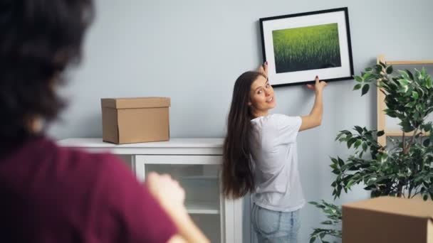 Esposo y esposa eligiendo lugar para la imagen en la nueva casa hablando y haciendo gestos — Vídeo de stock