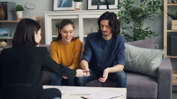 Hombre firma contrato tomando la clave de bienes raíces estrechando la mano y besar a la esposa — Vídeo de stock