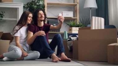 Genç adam ve kadın yeni daire akıllı telefon kullanarak online video arama yapma
