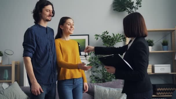 Uomo e donna che comprano casa prendendo chiave stringendo la mano con agente immobiliare poi baciare — Video Stock