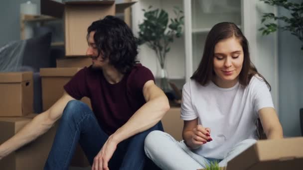 Happy par uppackning saker i ny lägenhet leende talar om interiör — Stockvideo