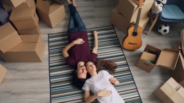Kutularla yeni düz halı üzerinde yatarken konuşan mutlu adam ve kadının üst görünümü