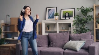 Genç kadın müzik şarkı dinlemek evde kanepede atlama dans