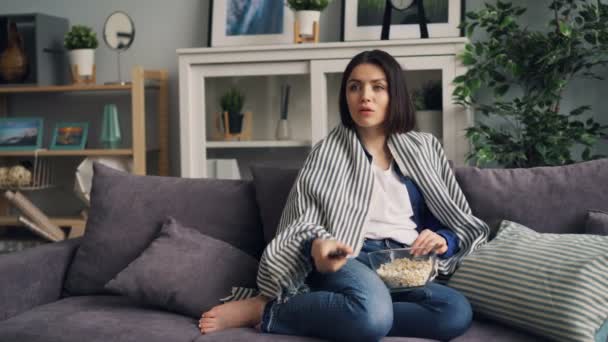 Giovane signora guardando la TV ridere e mangiare popcorn divertirsi a casa da solo — Video Stock