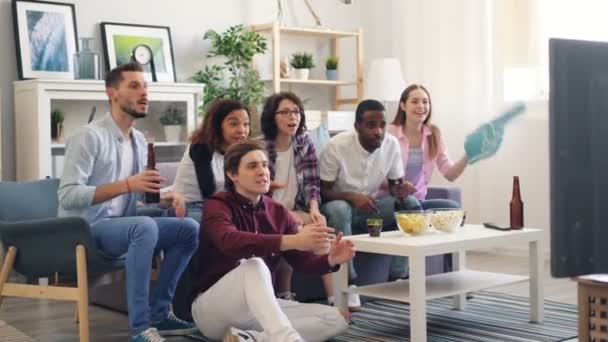 Homens e mulheres fãs estão desfrutando de jogo de esportes na TV em casa rindo abraços — Vídeo de Stock