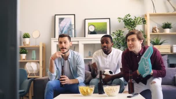 Jovens felizes comemorando gol durante jogo de futebol na TV fazendo high-five — Vídeo de Stock