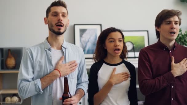 Jóvenes patriotas de pie cantando himno en casa antes de los juegos deportivos mundiales en la televisión — Vídeos de Stock