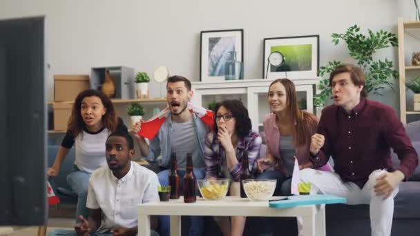 Jóvenes canadienses con banderas viendo deportes en la televisión haciendo high-five y abrazos — Vídeo de stock