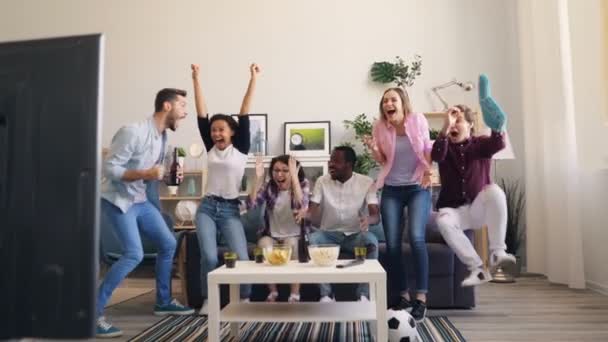 Chicas y chicos bailando y riendo después de la victoria en el juego de deportes en la televisión en casa — Vídeos de Stock