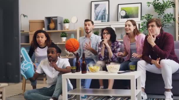 Fãs de basquete assistindo jogo de esportes na TV em casa apoiando equipe favorita — Vídeo de Stock