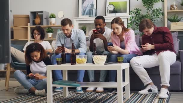 Мультирасовая группа друзей, использующих смартфоны для прикосновения к экрану на диване дома — стоковое видео