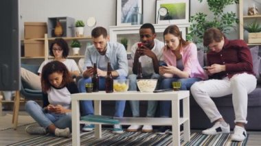 Akıllı telefonları kullanan neşeli arkadaşlar daha sonra Tv izliyor ve haberleri tartışıyor