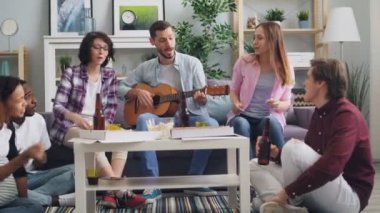Evde ki partide gitar çalarken, şarkı söylerken ve içerken eğlenen öğrenciler