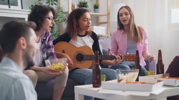 Multiethnische Gruppe von Freunden, die zu Hause auf einer Party singen und Gitarre spielen — Stockvideo