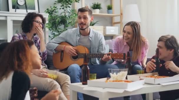 Happy friends bermain gitar, bernyanyi dan tertawa di pesta di apartemen — Stok Video