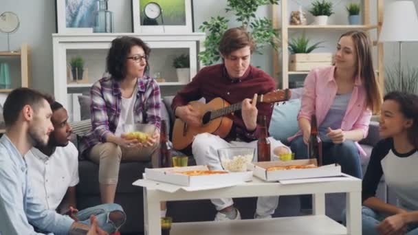 Radostné lidi zpívající na kytaru popíjí pivo doma v domácí party — Stock video