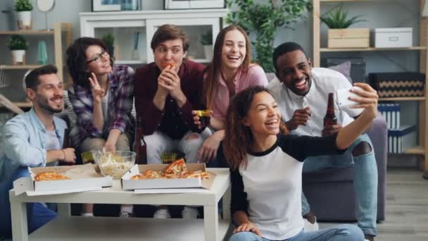 Jovens alegres tirando selfie com pizza e bebidas na festa usando smartphone — Vídeo de Stock