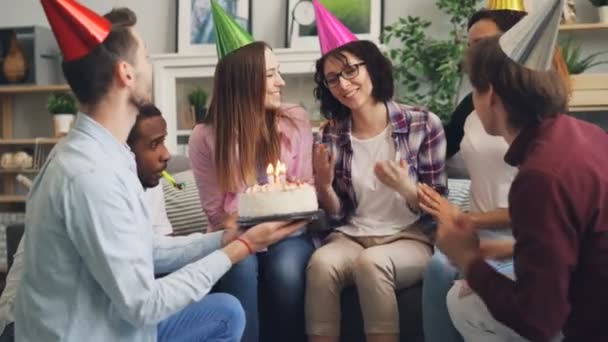 Jovem senhora fazendo desejo soprando velas no bolo de aniversário na festa com amigos — Vídeo de Stock