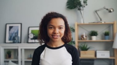 Sevimli Afro-Amerikan kız yavaş hareket portre gülümseme ile kameraya bakarak