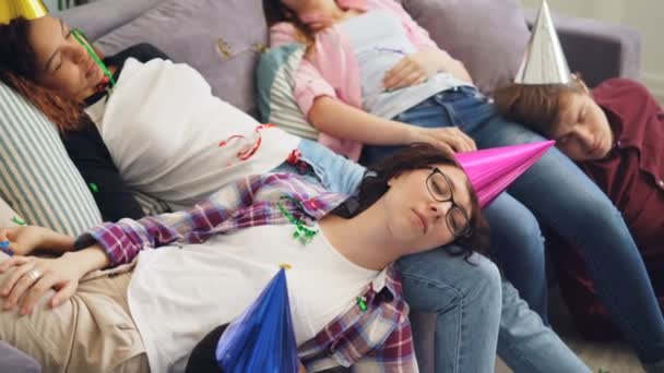Άνδρες και γυναίκες σε κόμμα καπέλο ύπνου στον καναπέ και το πάτωμα μετά από γιορτή στο σπίτι — Αρχείο Βίντεο