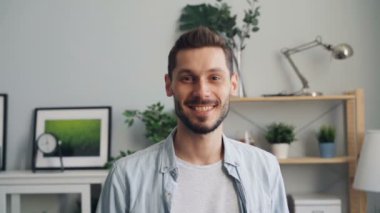 Mutlu adamın gülümseyen ve evde tek başına duran kameraya bakan portresi